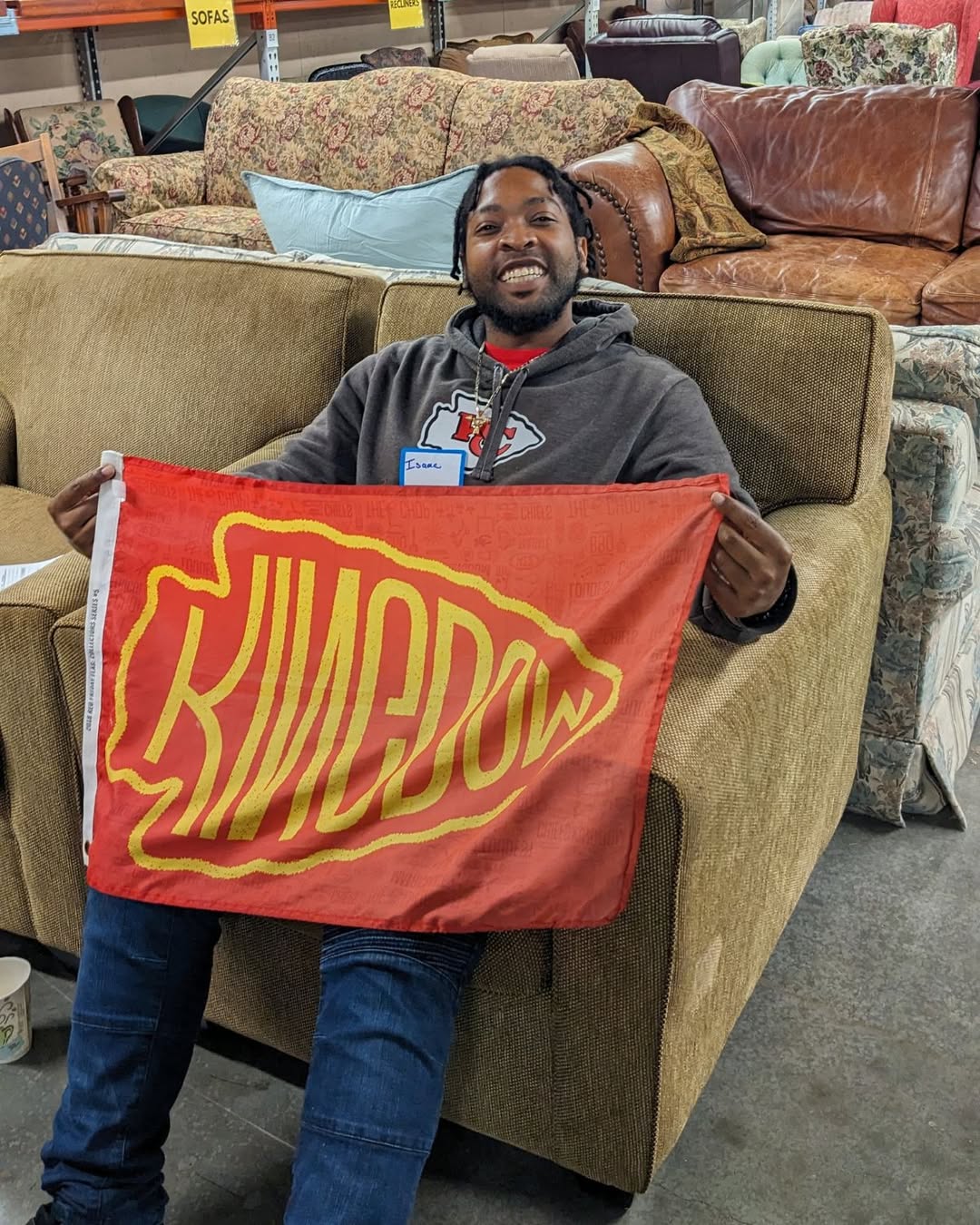 Isaac holds up a Chief's Kingdom flag after finding the perfect sofa